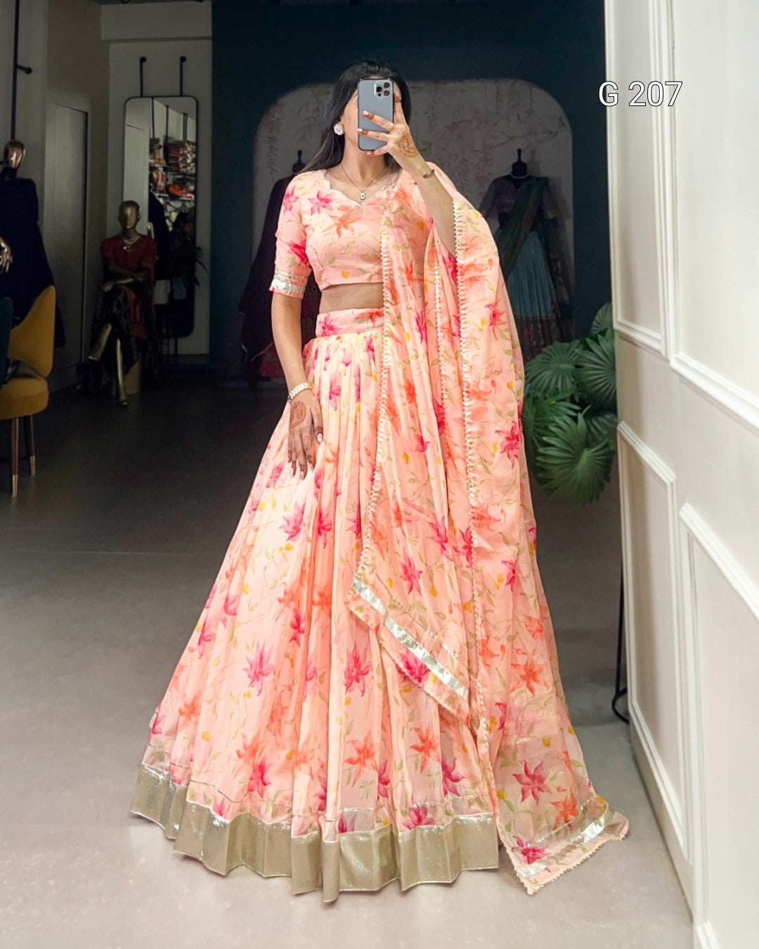 Person wearing a floral pink saree with a white border in a room.