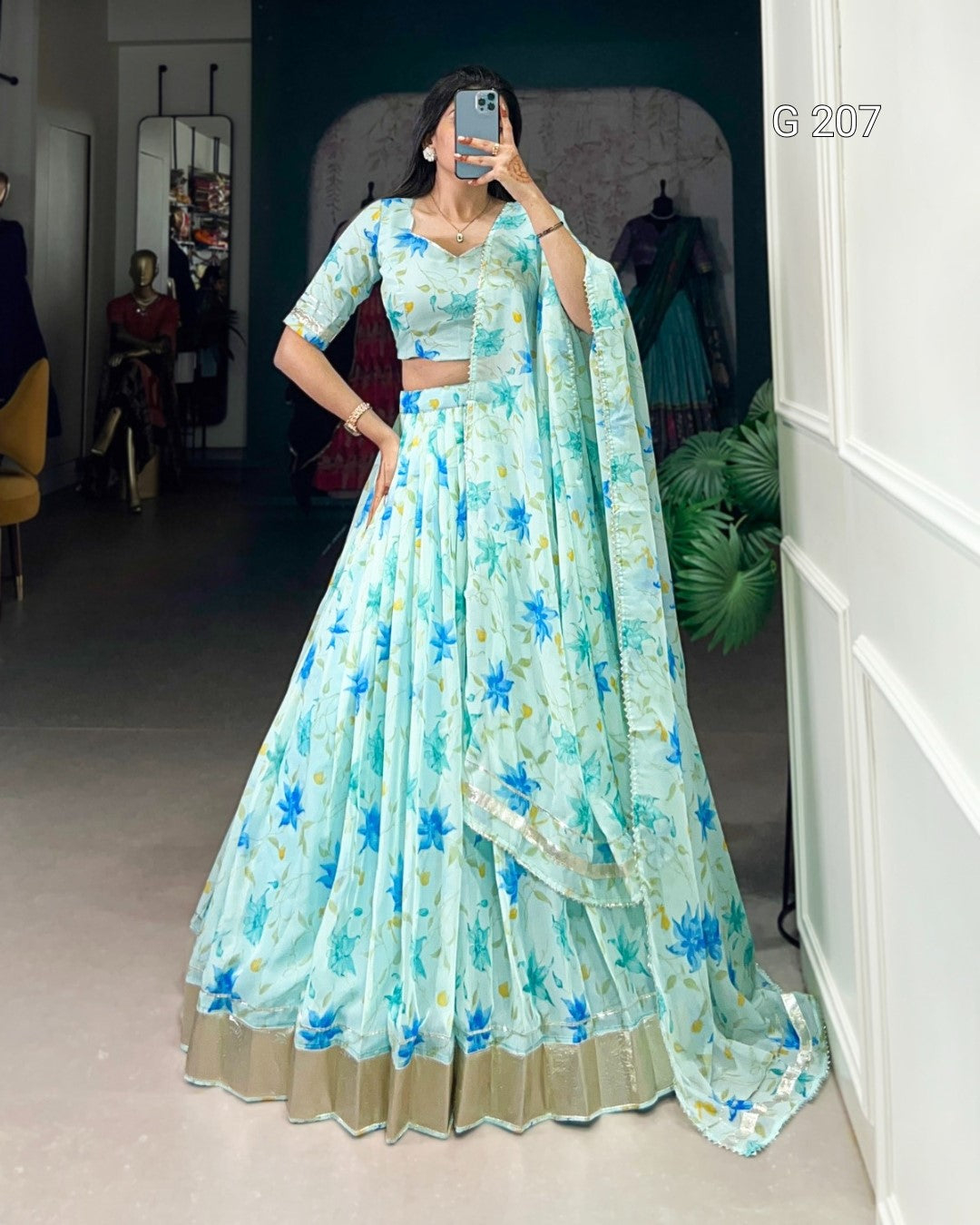 Woman wearing a light blue floral lehenga in front of a mirror.