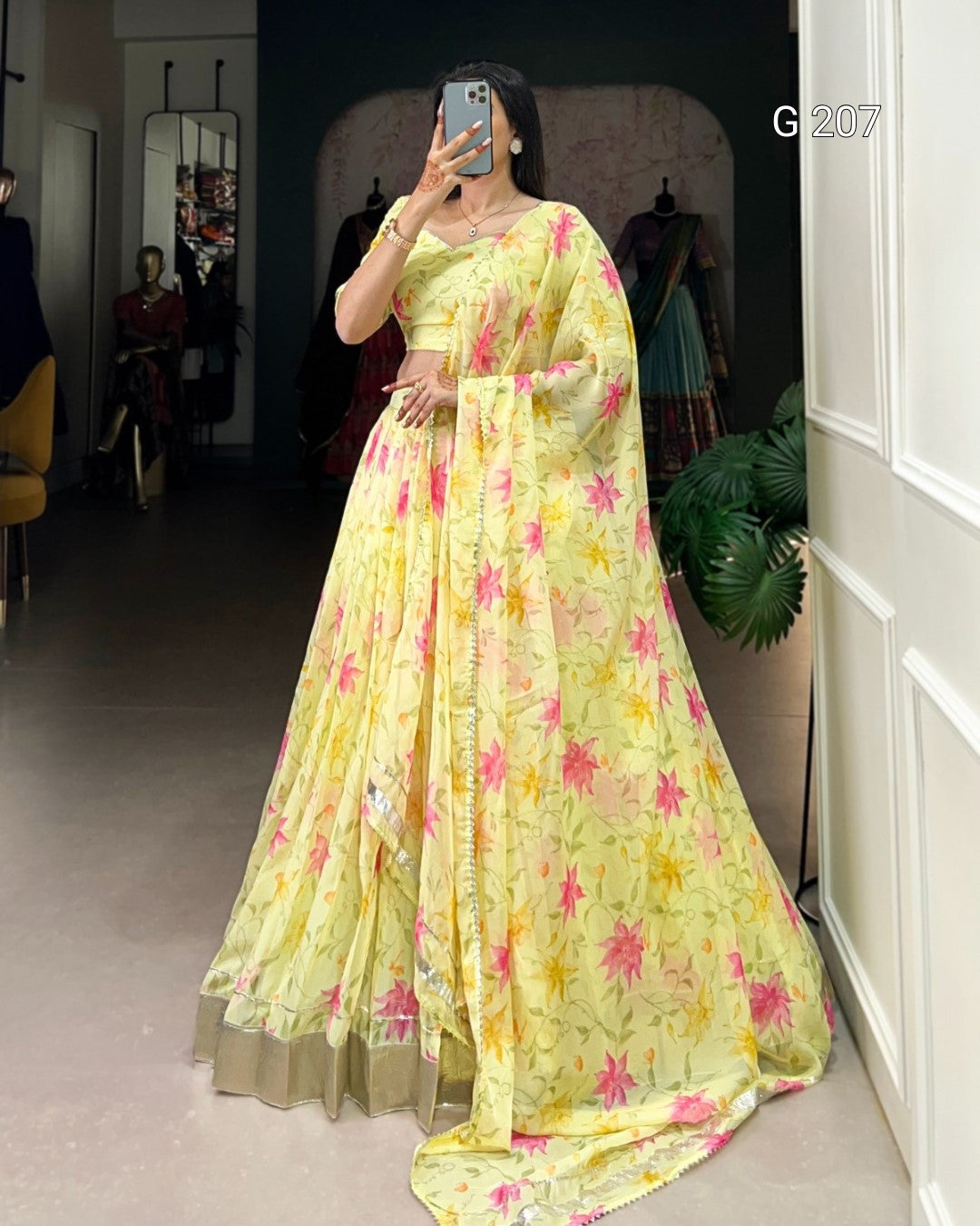 Woman wearing a yellow floral saree in a room with mirrors and furniture.