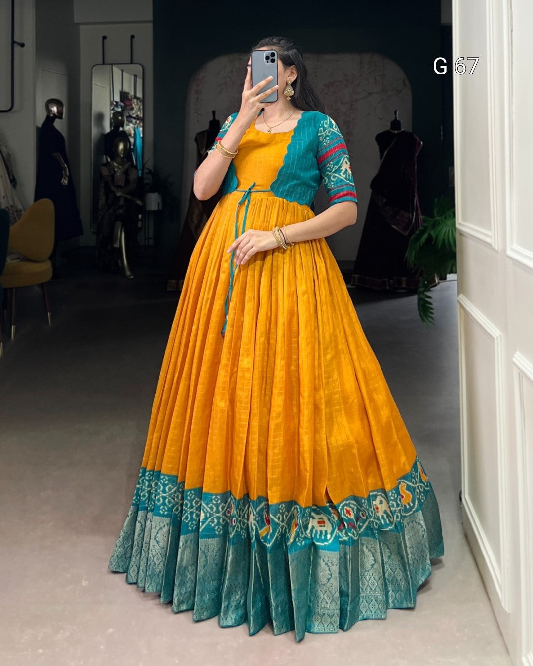 Person wearing a yellow and teal traditional outfit in a room.