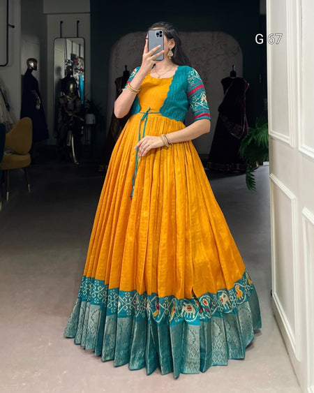 Person wearing a yellow and teal traditional outfit in a room.