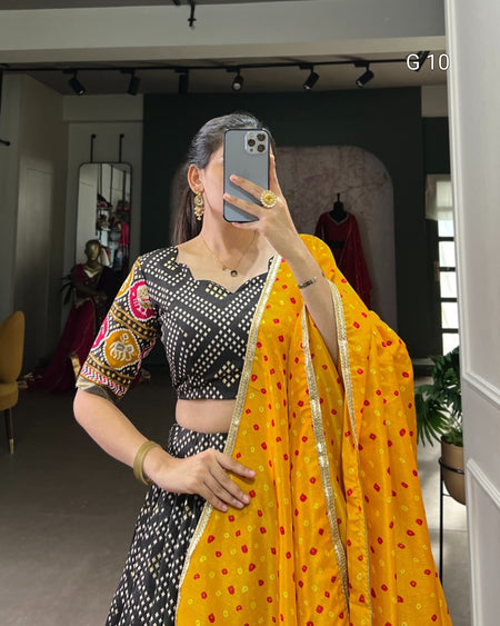 Person wearing a black and white patterned blouse with a yellow saree in a room.