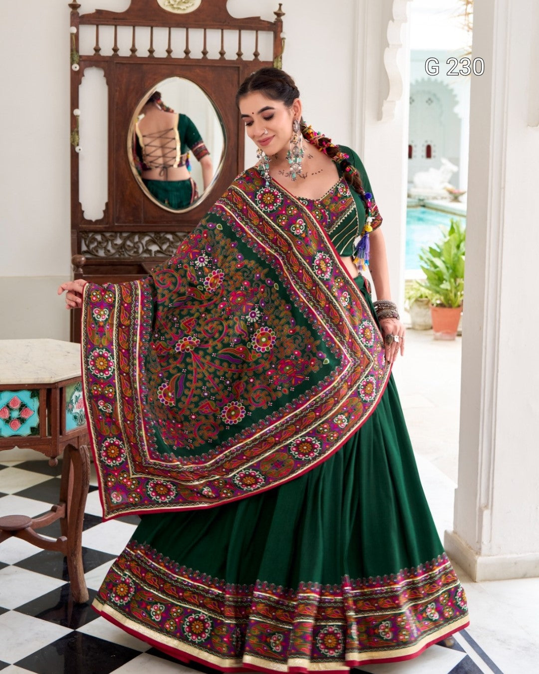 Woman in a green saree with a colorful dupatta in an indoor setting.