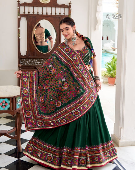 Woman in a green saree with a colorful dupatta in an indoor setting.