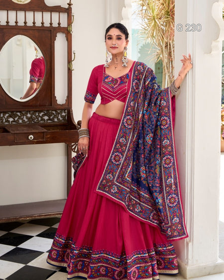 Woman in a pink traditional outfit with a patterned dupatta standing in a room.