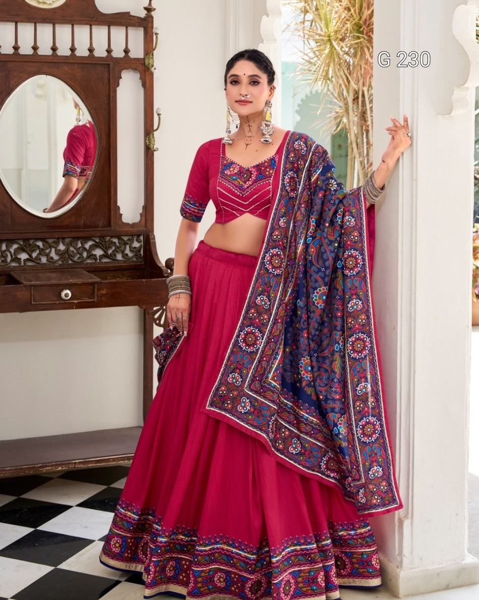 Woman in a pink traditional outfit with a patterned dupatta standing in a room.
