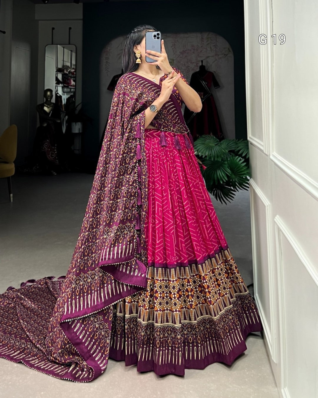Person wearing a traditional outfit with a pink and purple design in a room.