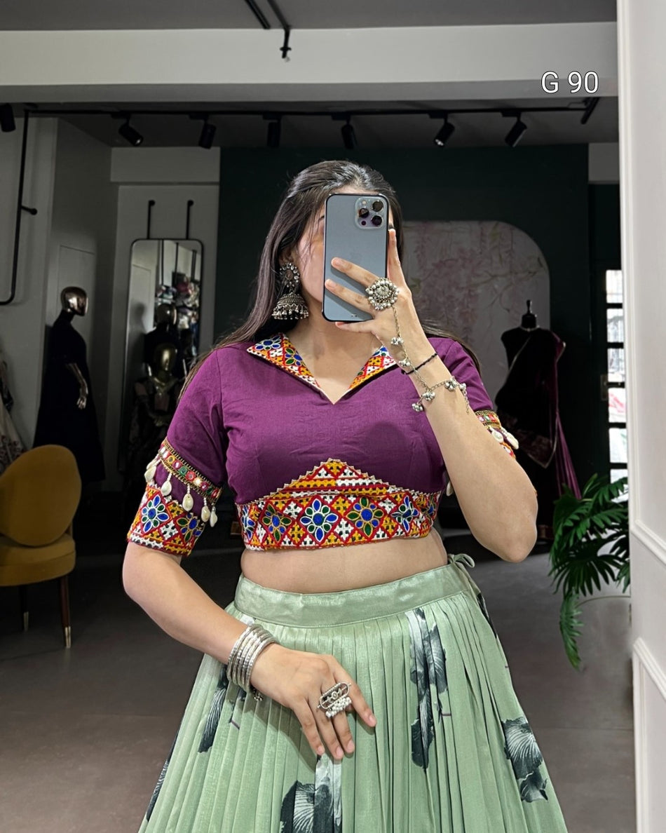 Person taking a mirror selfie wearing a purple blouse with colorful patterns and a green skirt.