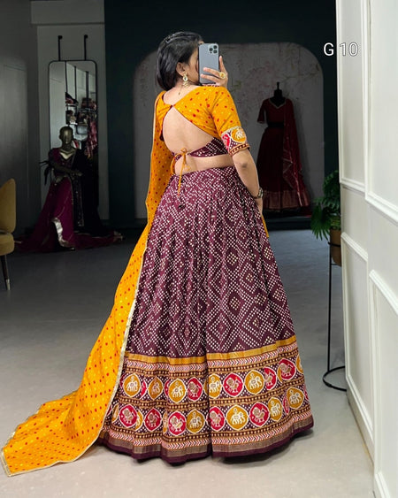 Woman wearing a traditional outfit with a yellow dupatta and patterned skirt in a room.