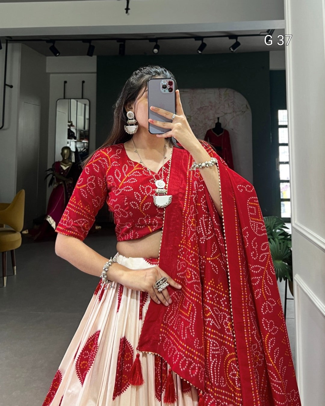 Person wearing a red and white traditional outfit with a matching dupatta in a room.