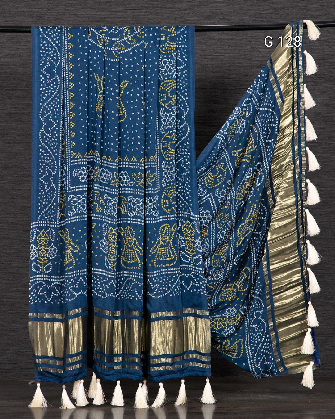 Blue and gold patterned fabric with white tassels on a dark background