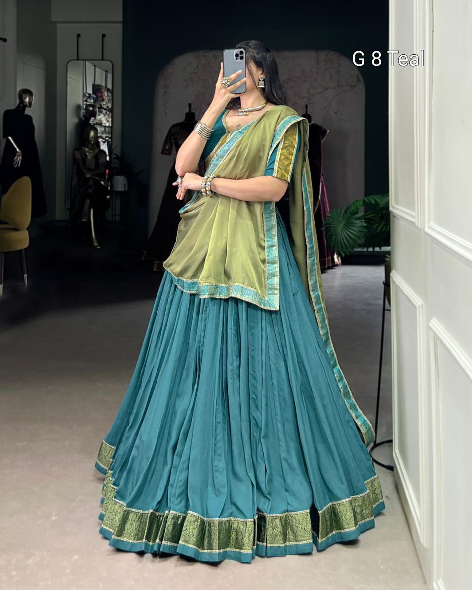 Woman wearing a teal and green traditional outfit taking a mirror selfie.