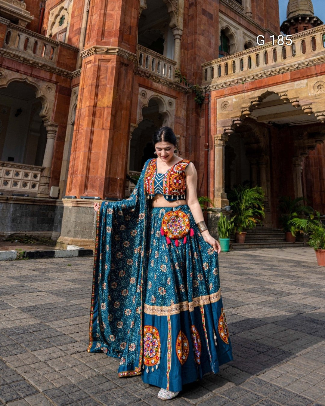 Woman in a blue traditional outfit standing in front of an architectural building.