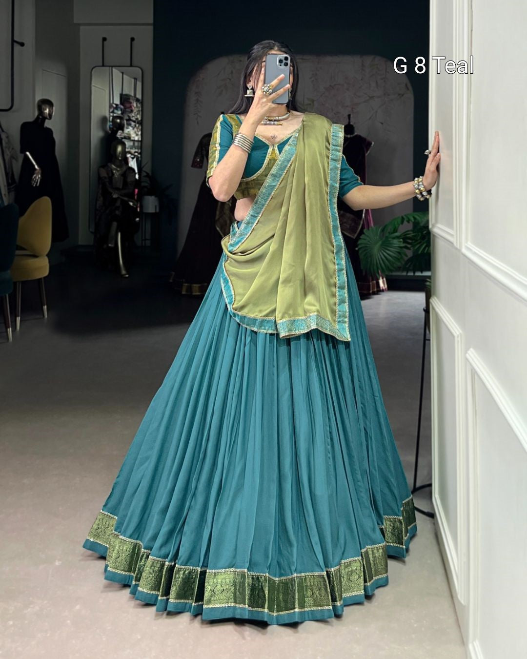 Person wearing a blue and green traditional outfit taking a mirror selfie.