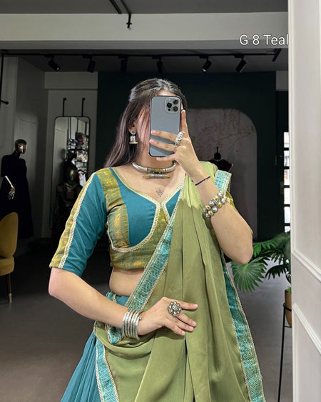 Woman taking a mirror selfie wearing a green and blue traditional outfit.