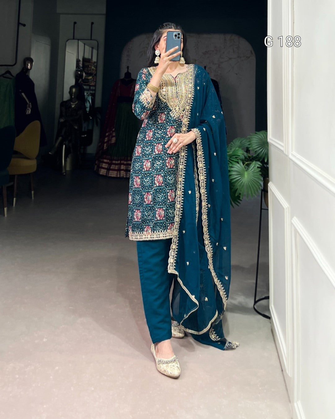 Woman in a blue embroidered traditional outfit taking a mirror selfie.