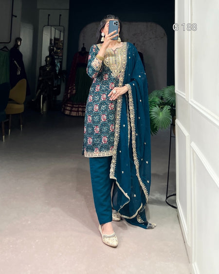 Woman in a blue embroidered traditional outfit taking a mirror selfie.