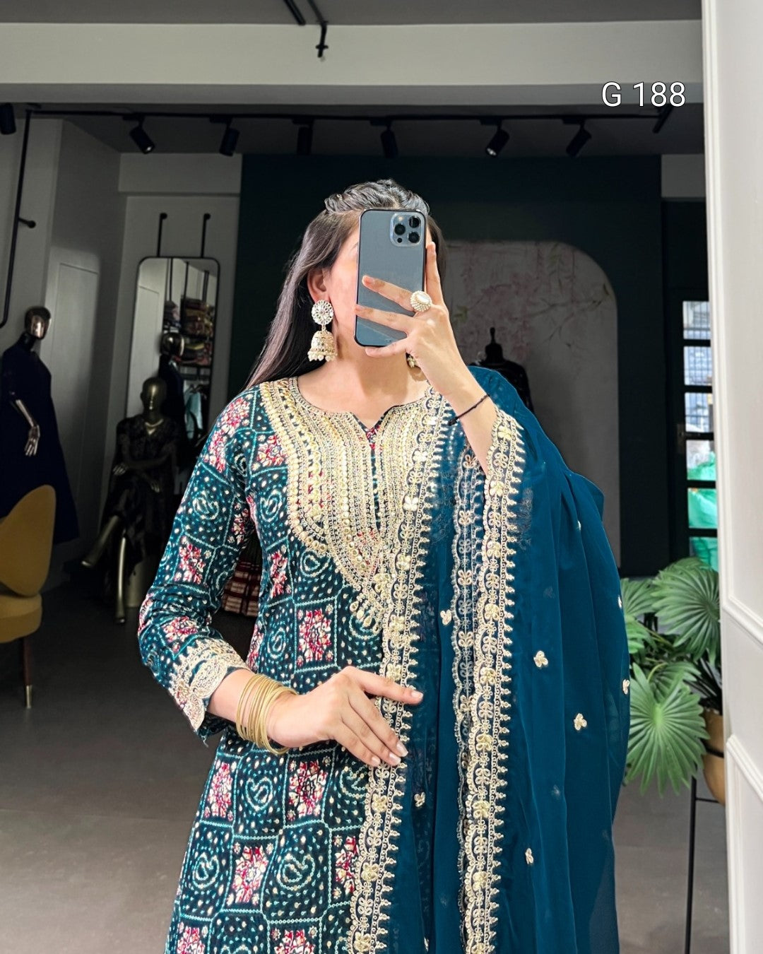 Person wearing a traditional outfit with intricate designs in a room setting.
