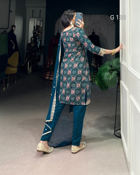 Person taking a mirror selfie wearing a traditional outfit with a floral top and blue pants.
