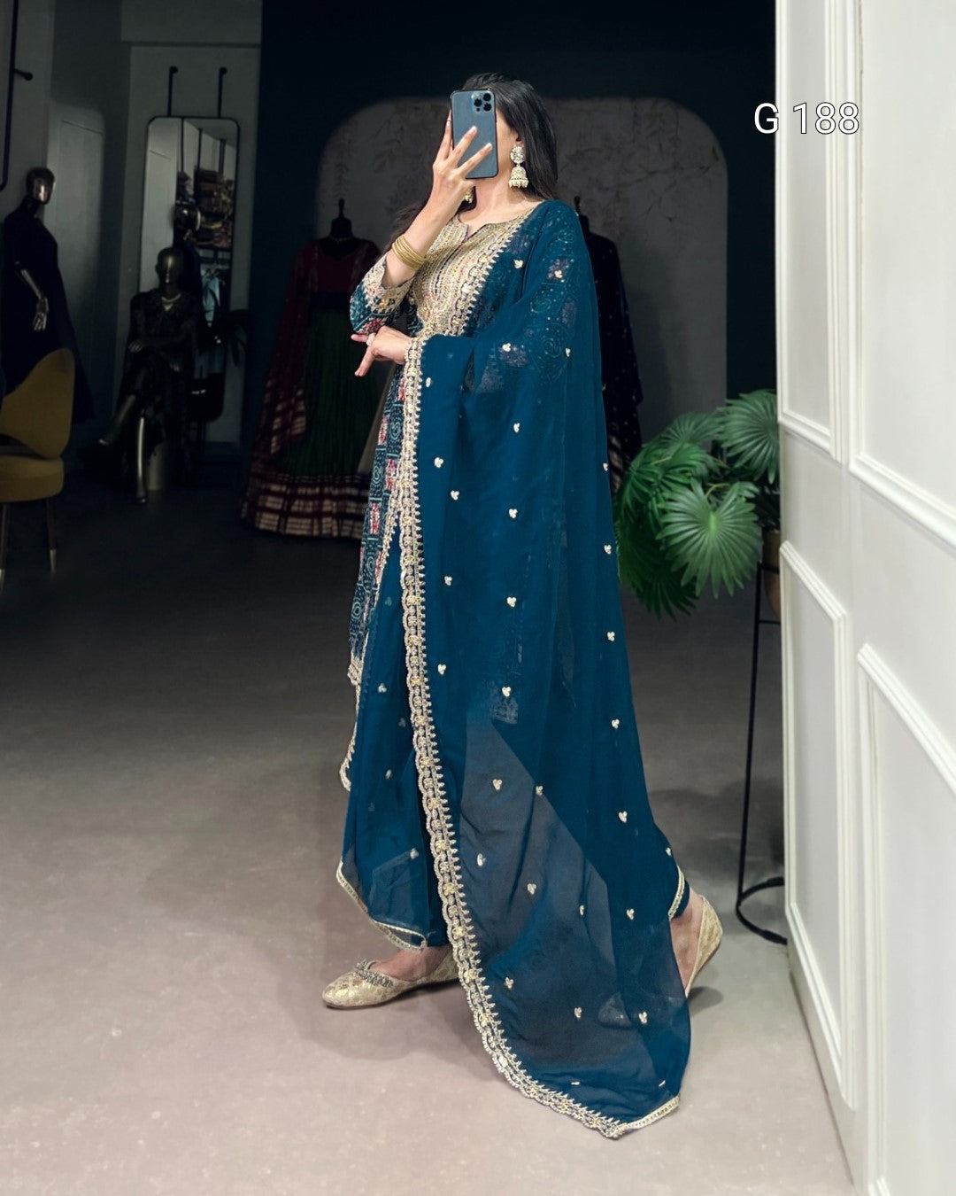 Person wearing a blue traditional outfit with intricate designs in a room.