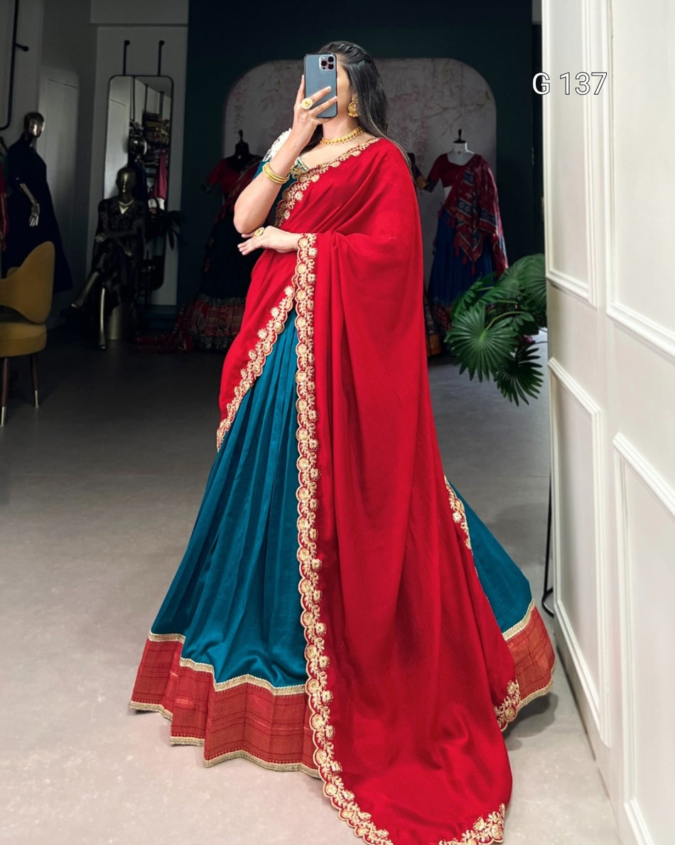 Person wearing a red and blue saree with gold border in a room.