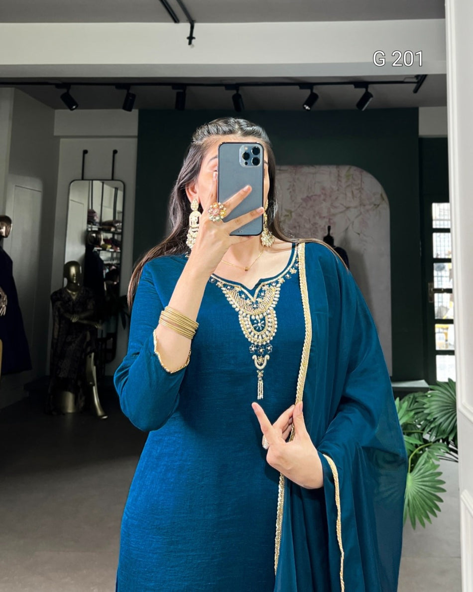 Woman in a blue traditional outfit taking a mirror selfie in an indoor setting.