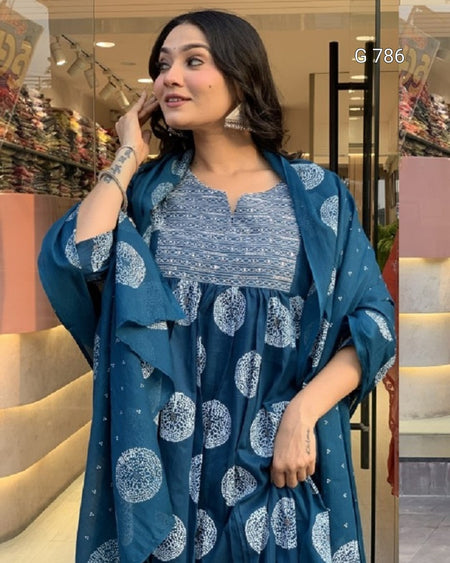 Woman wearing a blue patterned dress with a matching shawl indoors.