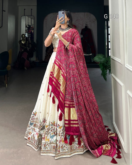 Person wearing a traditional outfit with a red and gold dupatta in a room.