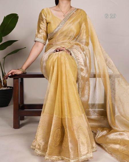 Woman wearing a yellow saree with a plain background