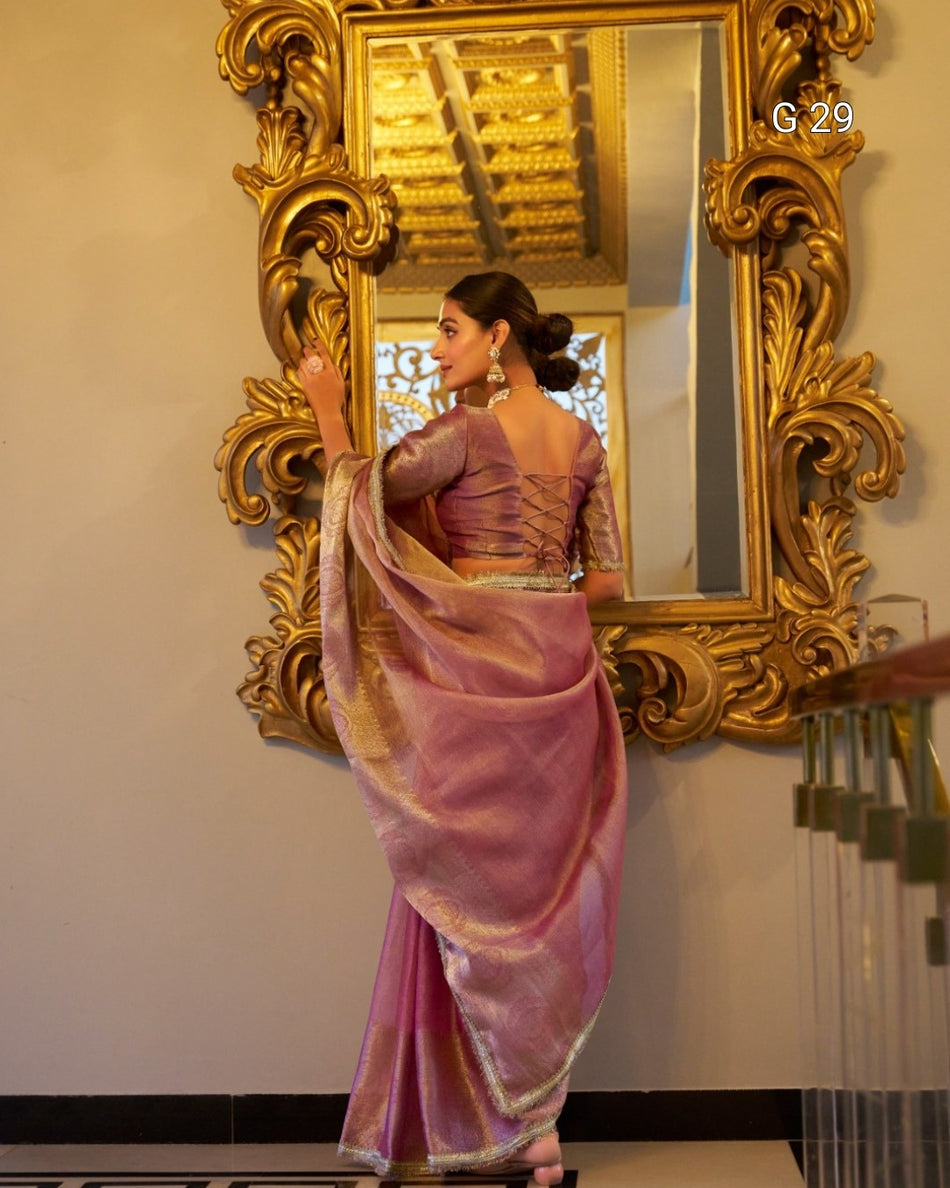 Woman in a pink saree standing in front of an ornate gold mirror.