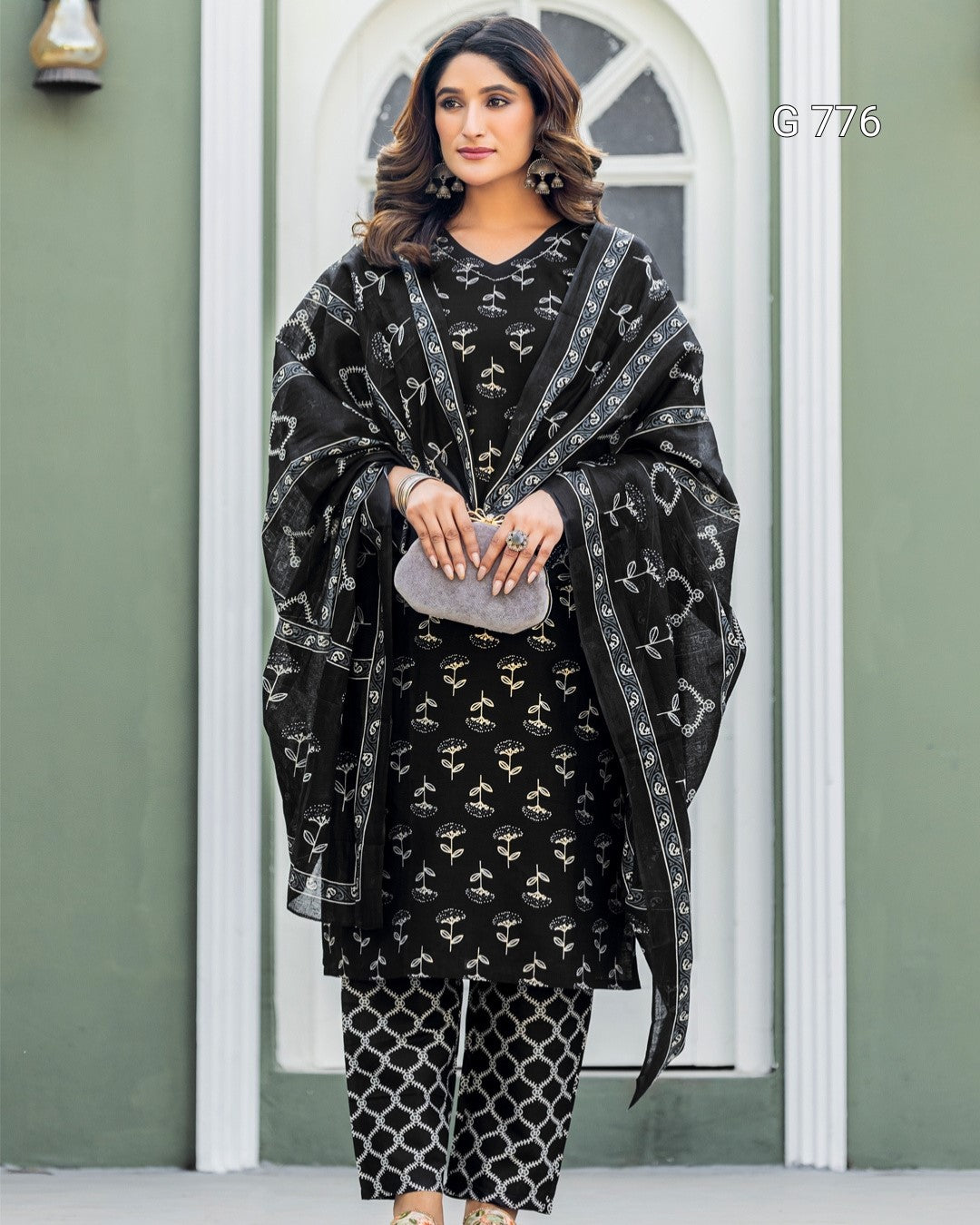 Woman wearing a black and white patterned outfit with a matching shawl indoors.