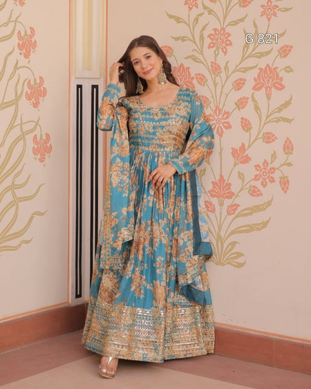 Woman in a floral dress standing against a decorated wall with floral patterns.