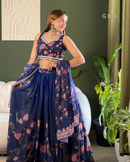 Woman in a floral saree standing in a room with green walls and plants.