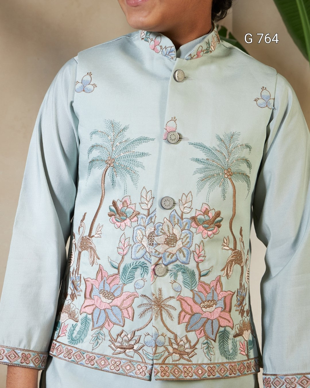 Light blue embroidered jacket with floral and palm tree designs on a beige background