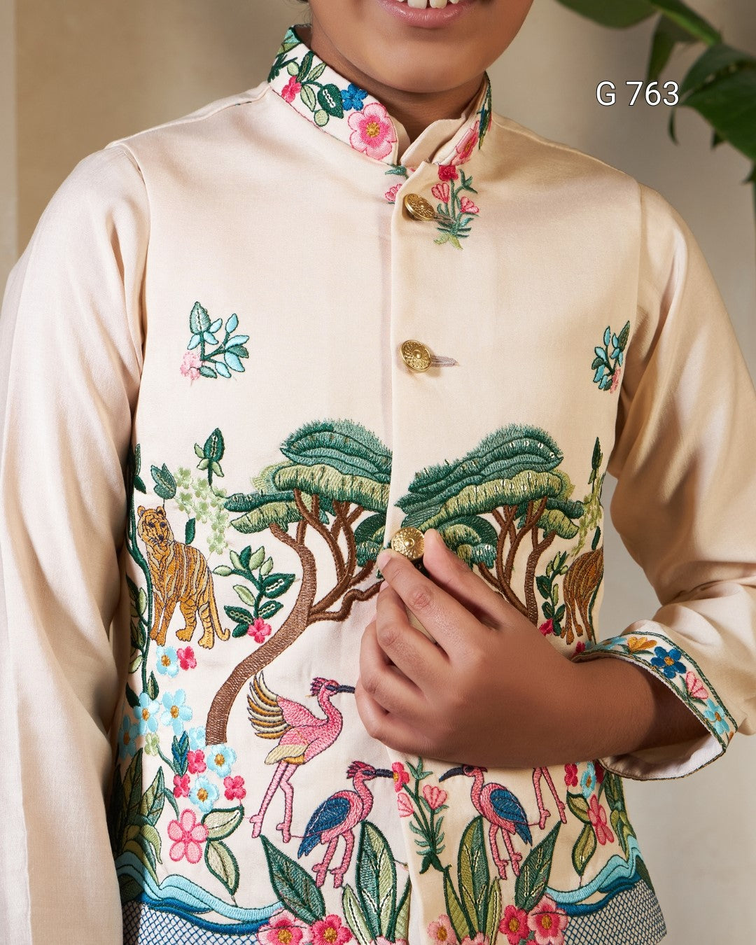 Beige embroidered shirt with colorful designs of animals and nature, held by a person.