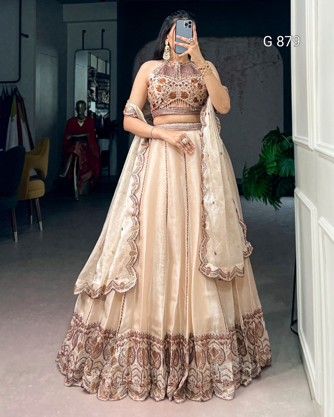 Person wearing a traditional beige and brown lehenga with intricate designs indoors.