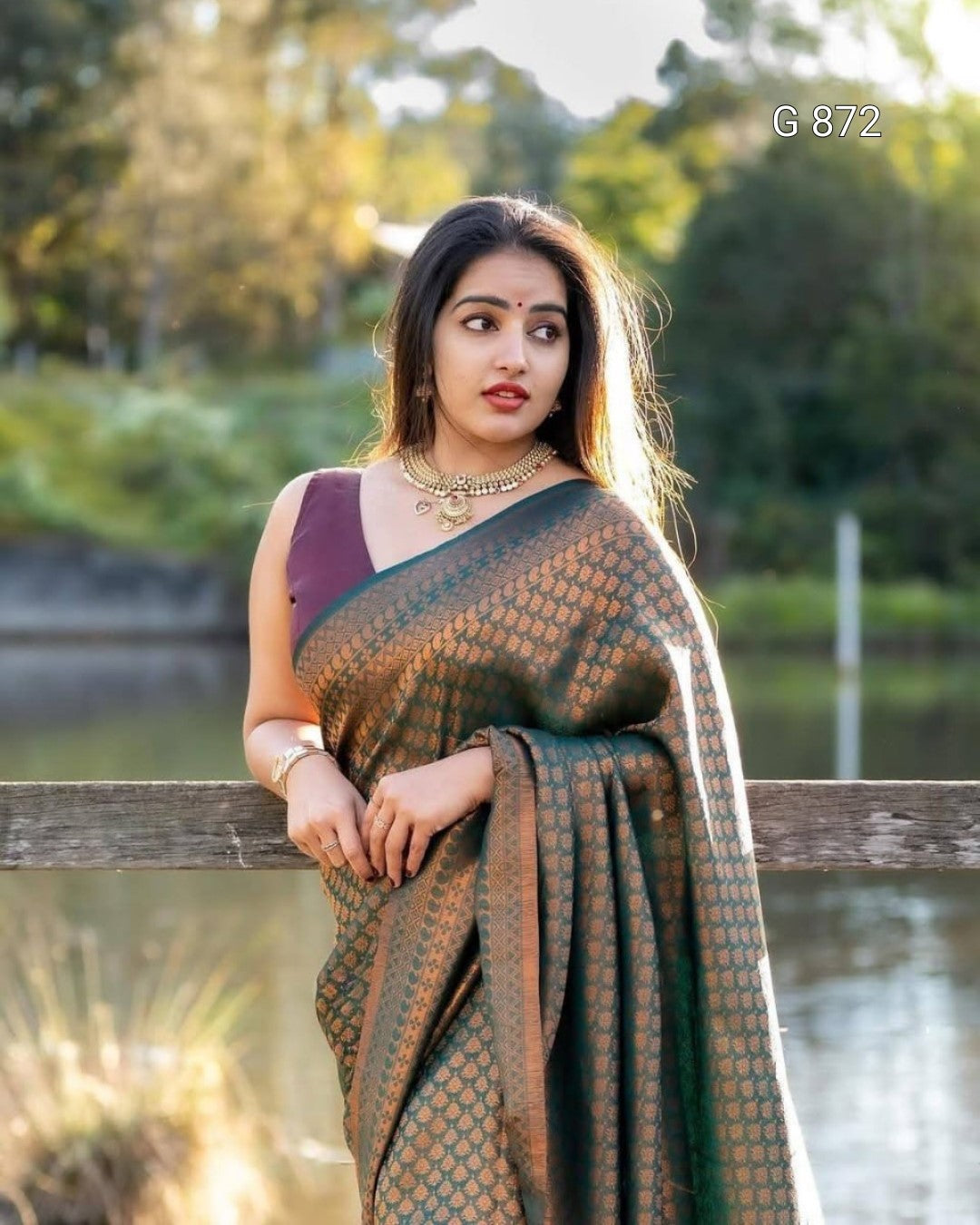 Woman in a saree standing outdoors by a body of water