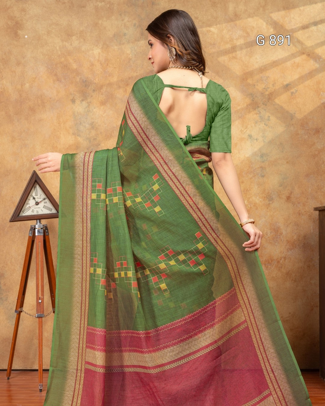 Woman wearing a green and red saree with a brown background