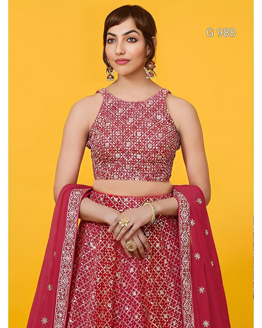 A woman models a red and pink lehenga choli set with intricate silver embroidery, set against a solid yellow background.