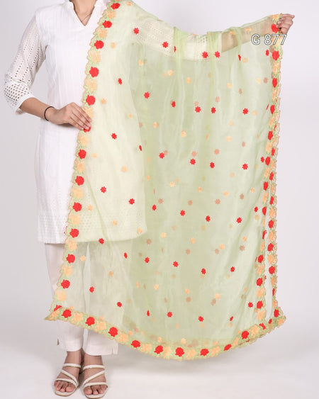 Light green scarf with red and yellow polka dots held by a person wearing a white outfit.