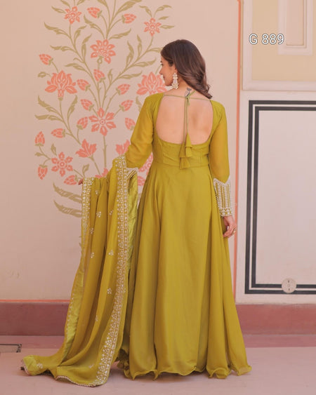Woman in a green dress with a floral wall and pink floor in the background