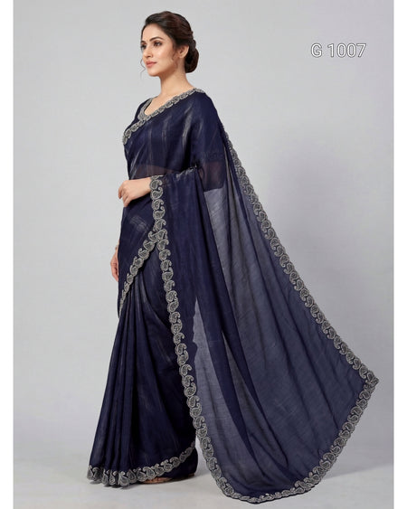 A woman modeling a navy blue saree with silver embroidered borders, standing against a light gray studio background. The text 'G 1007' appears in the top right corner.