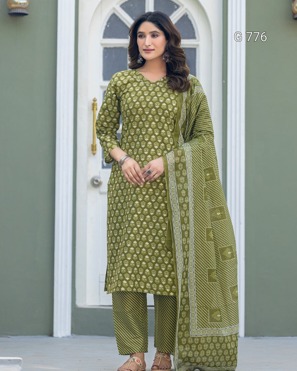Woman wearing a green traditional outfit with a matching dupatta in front of a white door.
