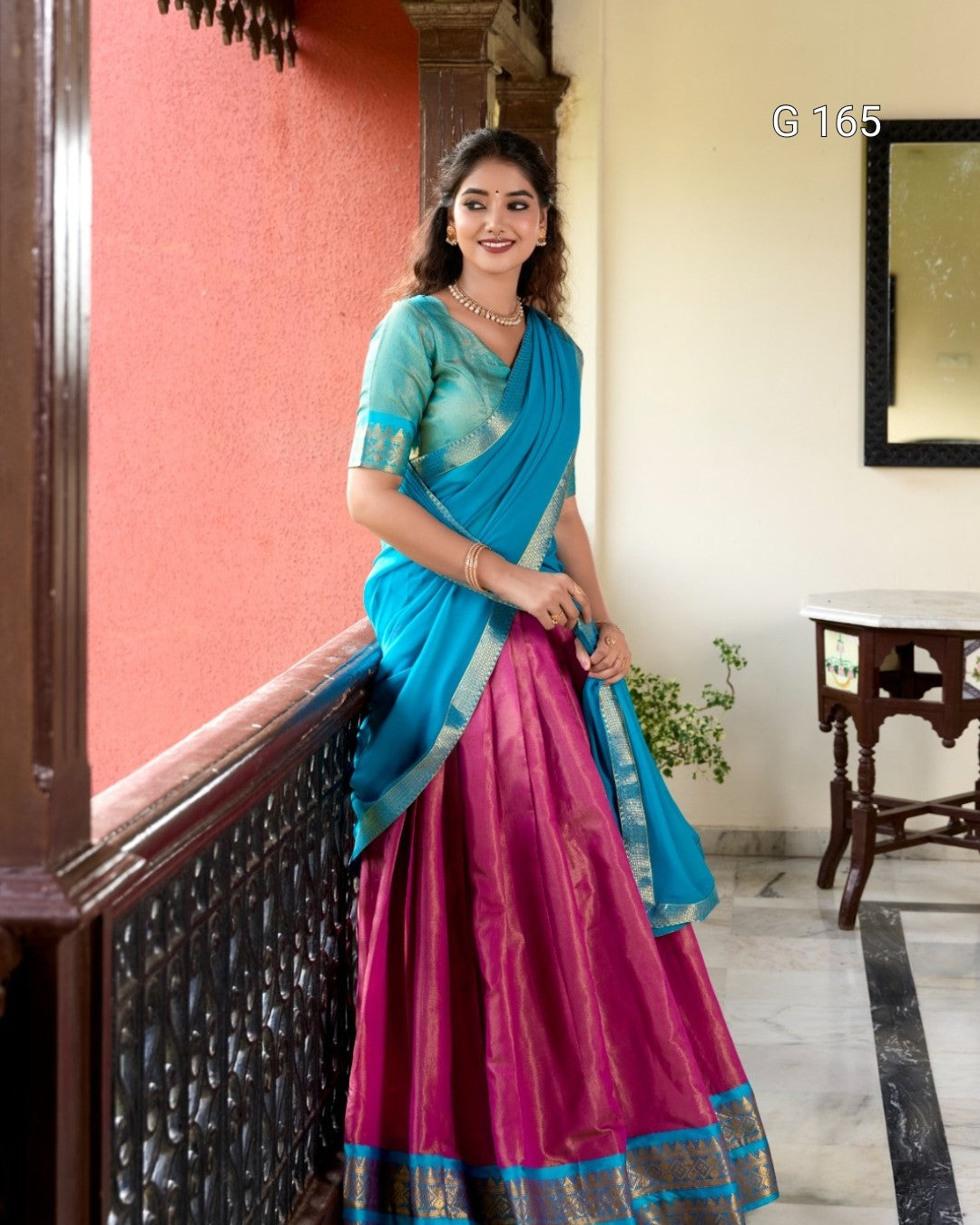 Woman wearing a blue and pink saree indoors.
