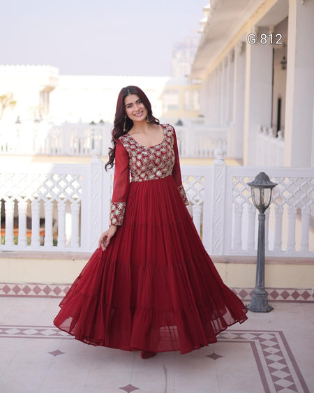 Woman in a red and gold traditional outfit standing on a balcony.