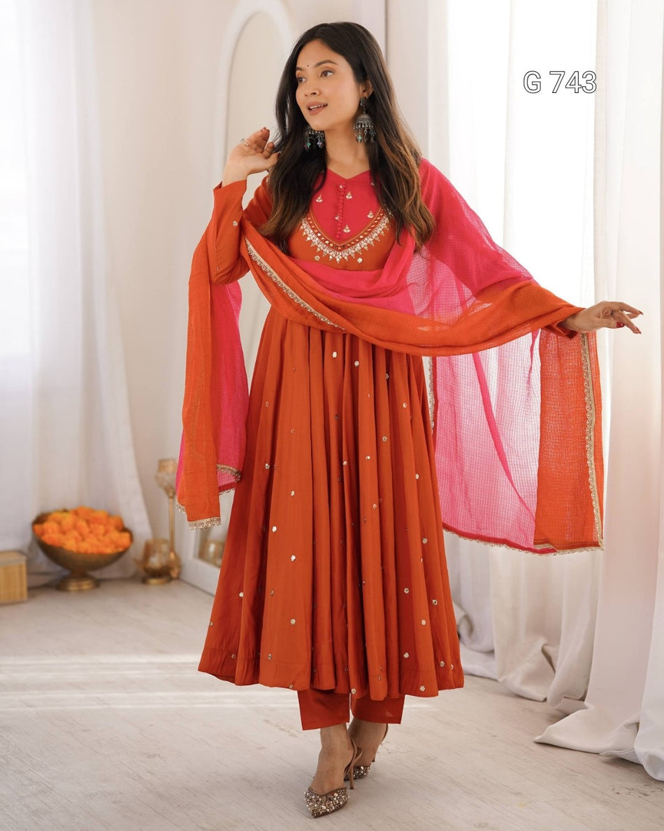 Woman wearing a traditional outfit with a red and pink dupatta in a well-lit room.