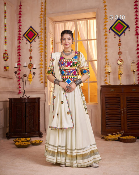 Woman in a colorful traditional outfit standing in a decorated room with hanging decorations and a window.