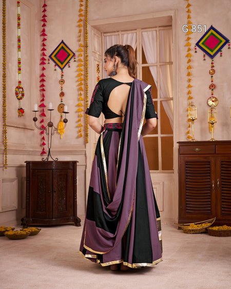 Woman wearing a purple and black saree in an ornate room.