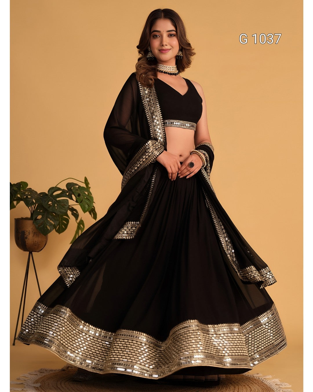 A woman models a black traditional Indian lehenga choli set with ornate silver mirror-work borders, set against a solid beige background.