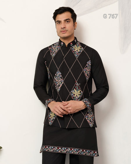 Man wearing a black embroidered kurta against a white background